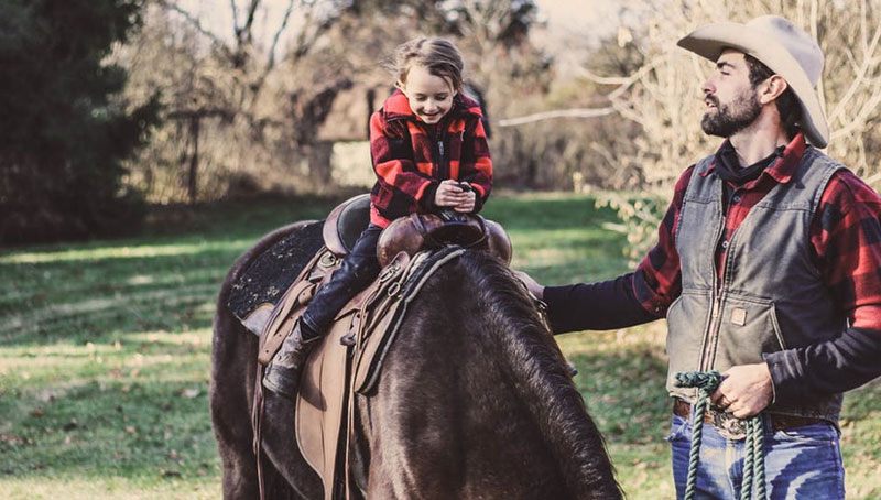 middle-aged man with his daughter riding a horse